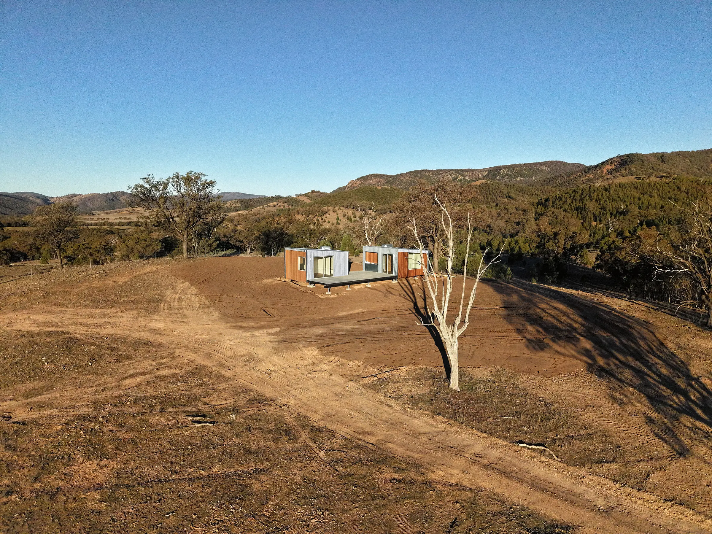 Two-module Arcopod cabin with an interconnecting deck in a rural Australian landscape